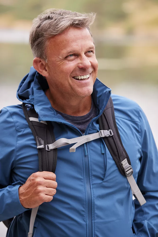 Adult man on a camping holiday looking away smiling, close up, Lake District, UK